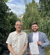 Two men standing on a sidewalk holding a piece of paper

AI-generated content may be incorrect.